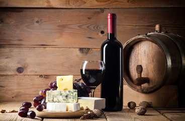 Red wine with various types of cheese on wooden background