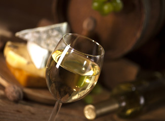 White wine with various types of cheese on wooden background