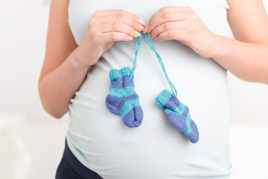 Pregnant woman holding little knitted socks
