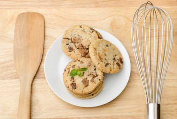 Homemade chocolate cookies on white plate and wooden background
