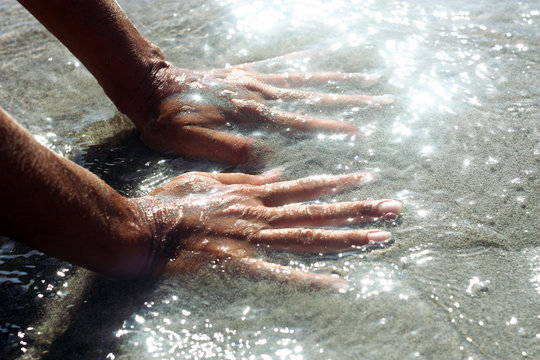 Mani di donna in acqua e sabbia
