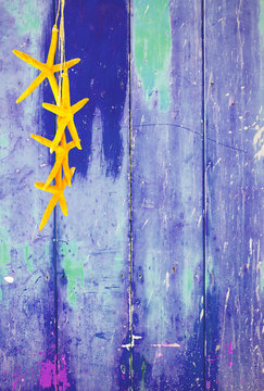 Blue colorful vintage background with shabby distressed grungy texture hippie style decorated with yellow starfish hanging from a straw string. 