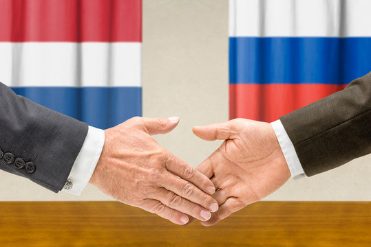 Vertreter der Niederlande und Russlands reichen sich die Hand