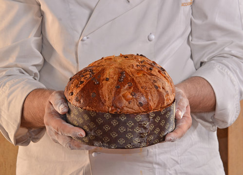 Manos de un panadero sujetando un panetone recien horneado.