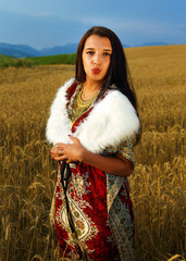 Smiling Young woman with ornamental dress standing on a wheat 