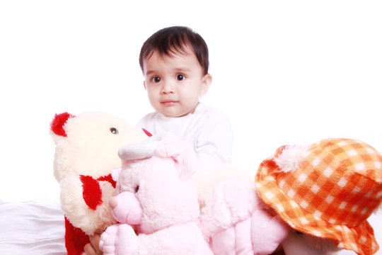 Baby playing with soft toys , photographed against white background