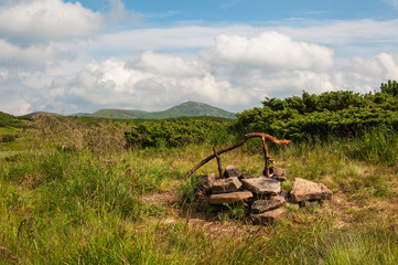 Fireplace on the green glade in mountains