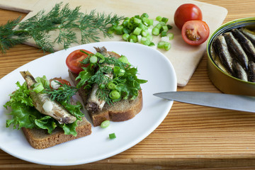 sprats, bread, onion and tomatoes on a table