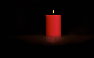 Red candle on a dark wooden floor.