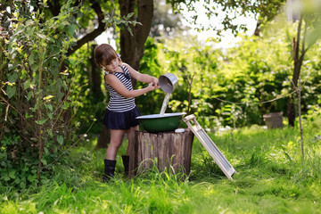 girl pours water into a basin from the scoop