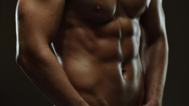 Young man showing work of muscles of body - abs