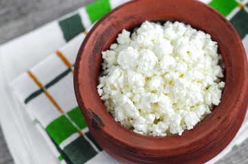 Crumbly homemade cottage cheese in a clay pot