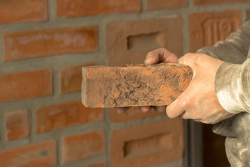 Men's hands are kept carved brick on brick wall background, man'