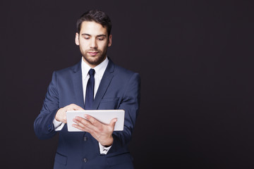 Businessman standing with a tablet computer on black background