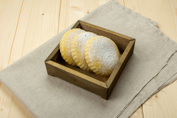 Three homemade milk biscuits with powdered sugar in a wooden box