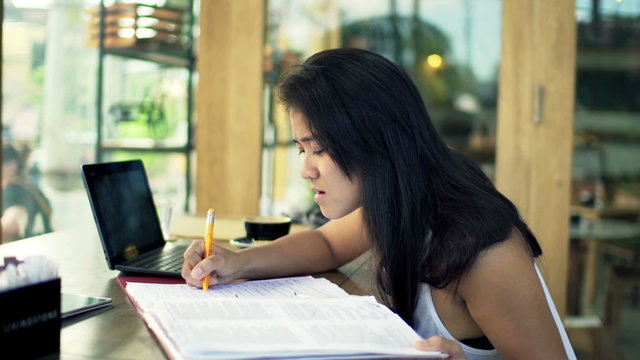 Young, sad female student overwhelmed by her homework in cafe 

