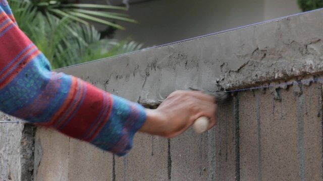 close-up hands of worker plastering concrete at wall of house construction in day time