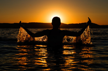 Silhouette of girl in the water at sunset