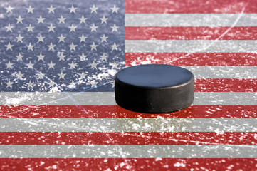 Black hockey puck on ice rink with flag of the United States © vencav