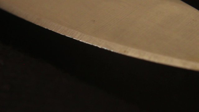 KNIFE BLADE - Medium Macro Dolly Move along the Cutting Edge; shot focuses on the edge with negative black space instead of centered blade