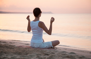 Young woman meditating on the sea coast