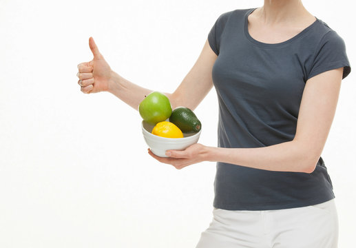 Young woman holding fresh fruits and showing thub up sign