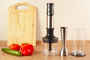 Fresh vegetables and a blender on the kitchen table