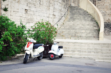 Two scooters parking in front of a stairway.