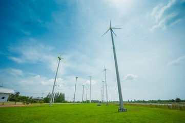 Fototapeta na wymiar Field of white wind turbines generating electricity on blue sky