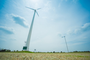 Field of white wind turbines generating electricity on blue sky