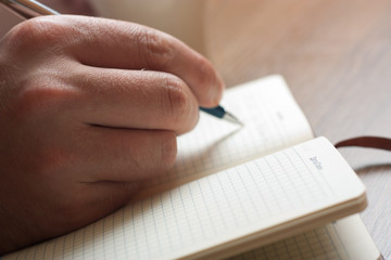 Close up of hand making notes in the writing pad