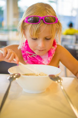 Adorable girl eat noodle soup on food court in mall
