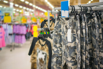 Bunch of military style trousers and t-shirts on hangers in stor