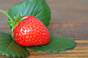 Strawberry and a leaf on wooden background