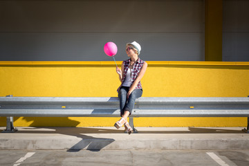 Toned photo of stylish hipster girl posing with pink balloon