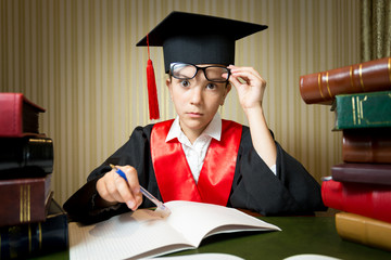 Portrait of smart girl in graduation clothes doing homework