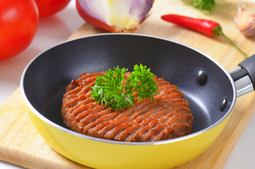Beef burger patty in pan