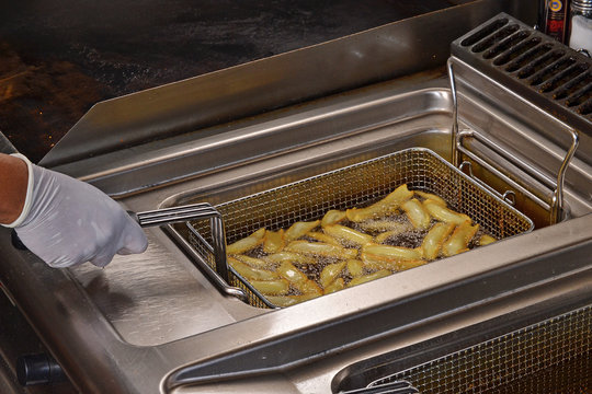 Cocinando patatas fritas en un freidor industrial.
