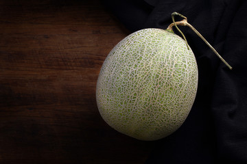 Fresh organic Japanese melon and black fabric on wooden table