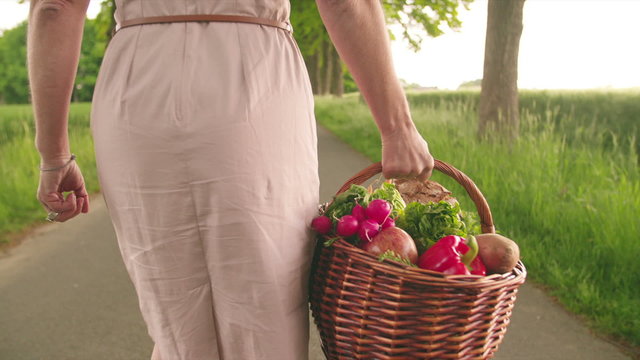 Woman holding a basket of vegetables in a park