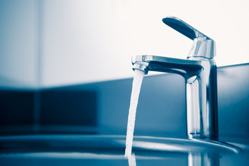 faucet with flowing water, blue tone