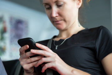 Portrait of businesswoman using smart phone.
Lady holding black telephone touching screen with finger dressed black shirt and grey pants face blurred focus on hands and telephone