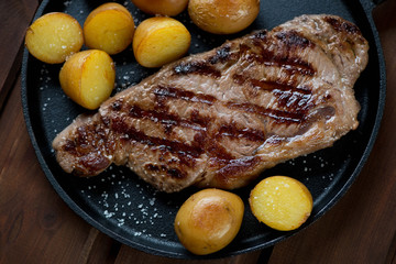 Close-up of grilled striploin beef steak and potato, top view