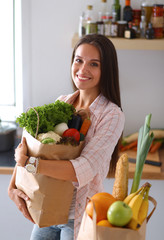 Young woman holding grocery shopping bag with vegetables 