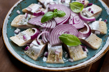 Sliced herring fillet with red onion and basil, close-up