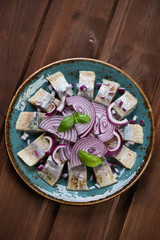 Herring fillet with red onion on a turquoise plate, top view