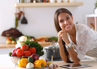 Young woman using a tablet computer to cook in her kitchen