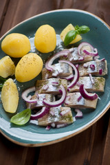 Sliced herring fillet with boiled potato, red onion and basil