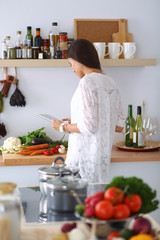 Young woman using a tablet computer to cook in her kitchen