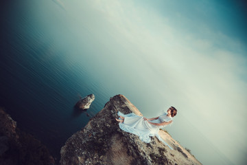 Beautiful bride posing on the coast with angelic dress.